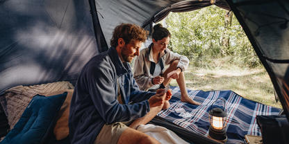 Ein P&auml;rchen spielt Karten beim Campen im Zelt.
