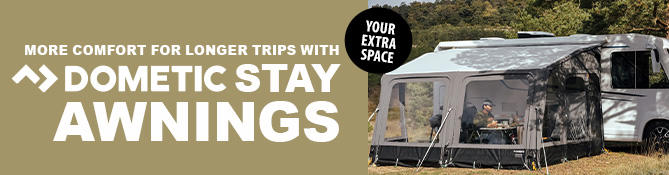 Caravan with an attached awning on grass, two people seated at a table under the awning, visible text: EINFACH L&Auml;NGER UNTERWEGS >> DOMETIC STAY VORZELTE and round badge DEIN EXTRA RAUM