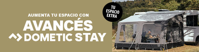 Caravana con toldo acoplado sobre c&eacute;sped, dos personas sentadas en una mesa bajo el toldo, texto visible: EINFACH L&Auml;NGER UNTERWEGS >> DOMETIC STAY VORZELTE y distintivo redondo DEIN EXTRA RAUM
