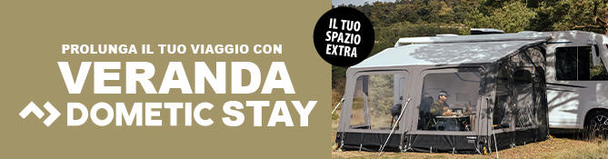 Roulotte con tenda annessa su prato, due persone sedute a un tavolo sotto la tenda, testo visibile: EINFACH L&Auml;NGER UNTERWEGS >> DOMETIC STAY VORZELTE e distintivo rotondo DEIN EXTRA RAUM