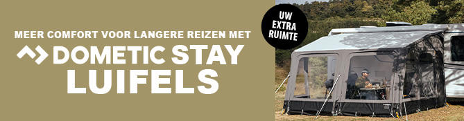 Caravan met aangebracht voortent op gras, twee zittende personen aan een tafel onder de voortent, zichtbare tekst: EINFACH L&Auml;NGER UNTERWEGS >> DOMETIC STAY VORZELTE en ronde sticker DEIN EXTRA RAUM