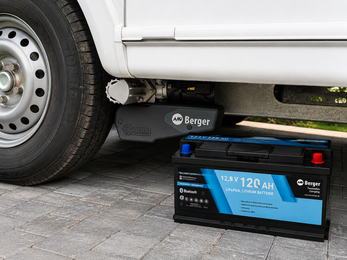 Wei&szlig;e Fahrzeugseite mit Stahlrad; darunter ein schwarzer Wagenheber mit Berger-Logo und daneben eine schwarz-blaue 12,8V 120 Ah Lithium-Batterie auf Pflastersteinen