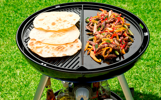 Grill mit Fleisch und Fladenbrot auf Rasen