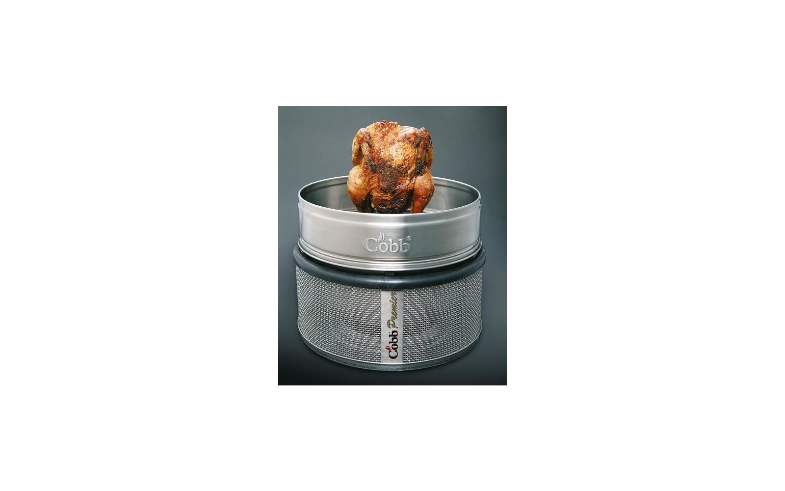 Braun gebräuntes ganzes Hähnchen auf rundem Metallgrill mit Aufschrift Cobb, grauer Hintergrund